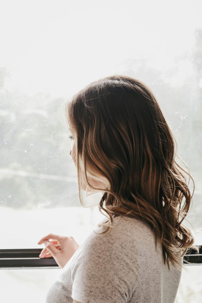 woman sitting quietly by a window perhaps reflecting on personal growth goals