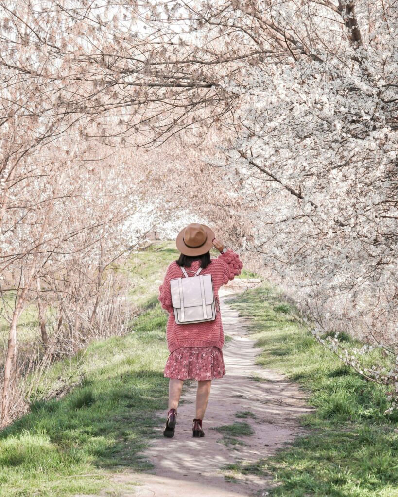 Midlife woman enjoying a spring nature walk surrounded by blooming trees