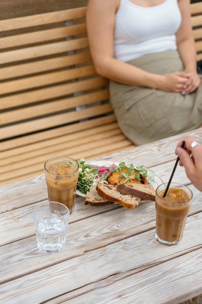 iced coffee drinks and a sandwich on a table outdoors