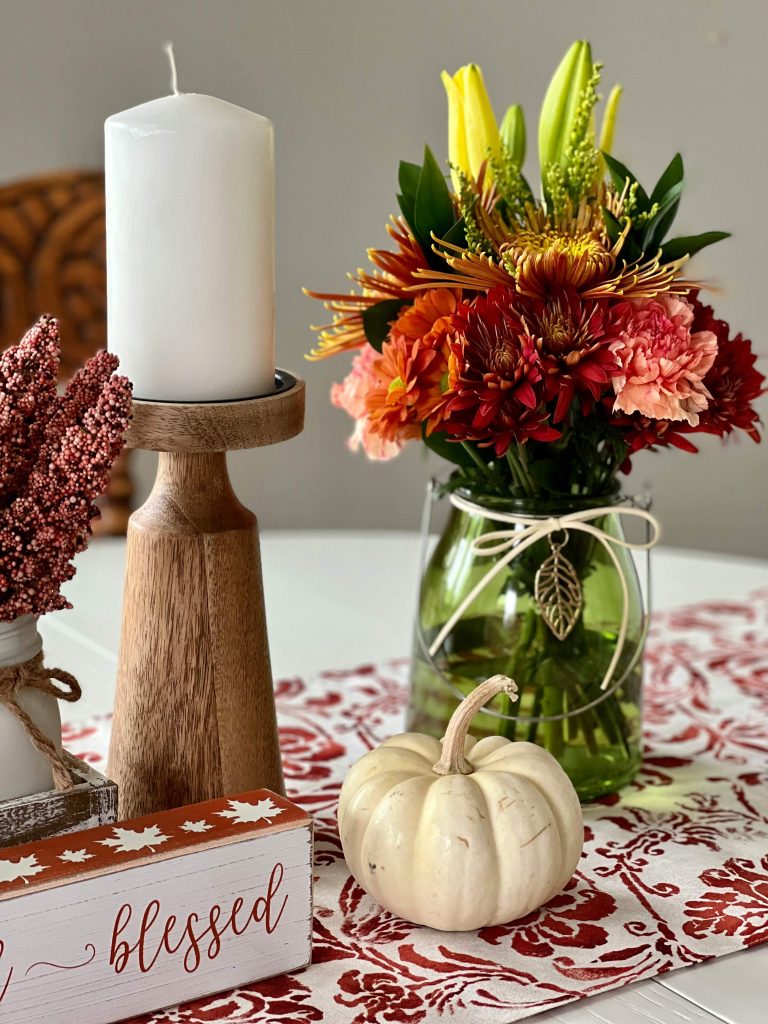 Affordable fall table centerpiece with pumpkins and candles, and fall foliage