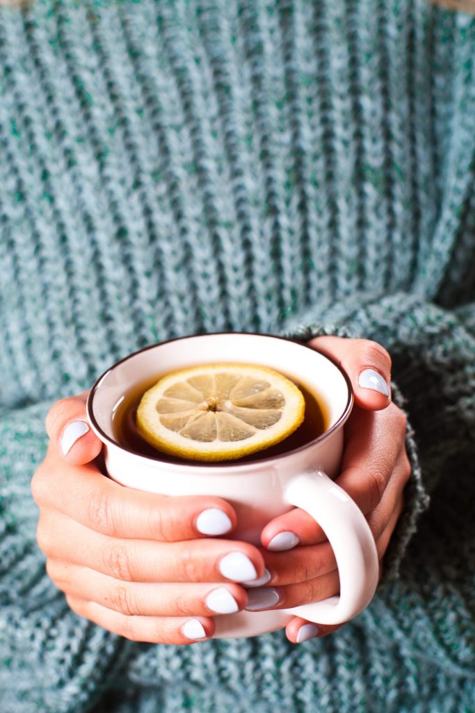 woman holding a cup of tea with lemon practicing mindfulness