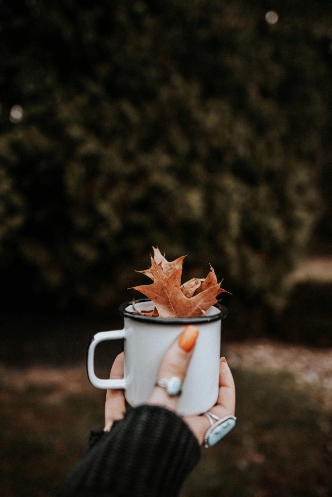 A warm drink surrounded by autumn leaves representing gratitude and personal growth.