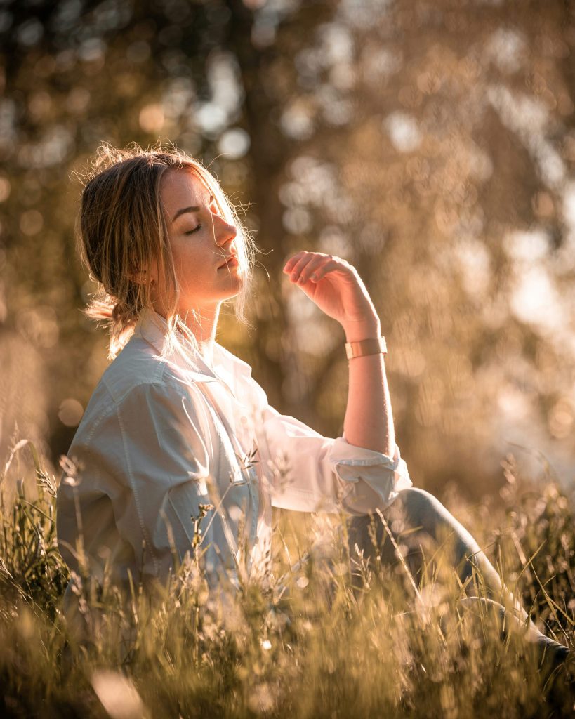 woman sitting outside in the sunlight enjoying a mindful moment