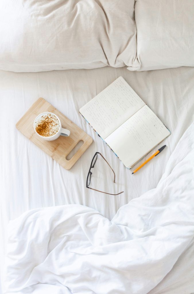 journal, coffee, glasses on a bed for a mindful morning routine