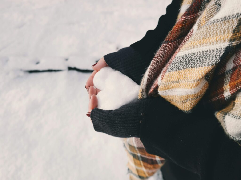 women outside holiding a snow in the shape of a heart